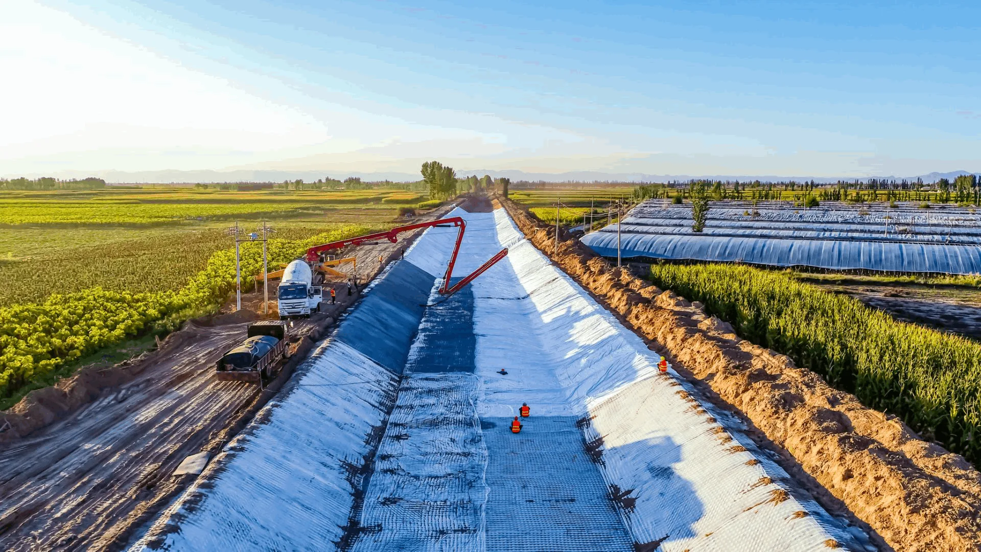 Aerial canal lining with pump arm in farmland