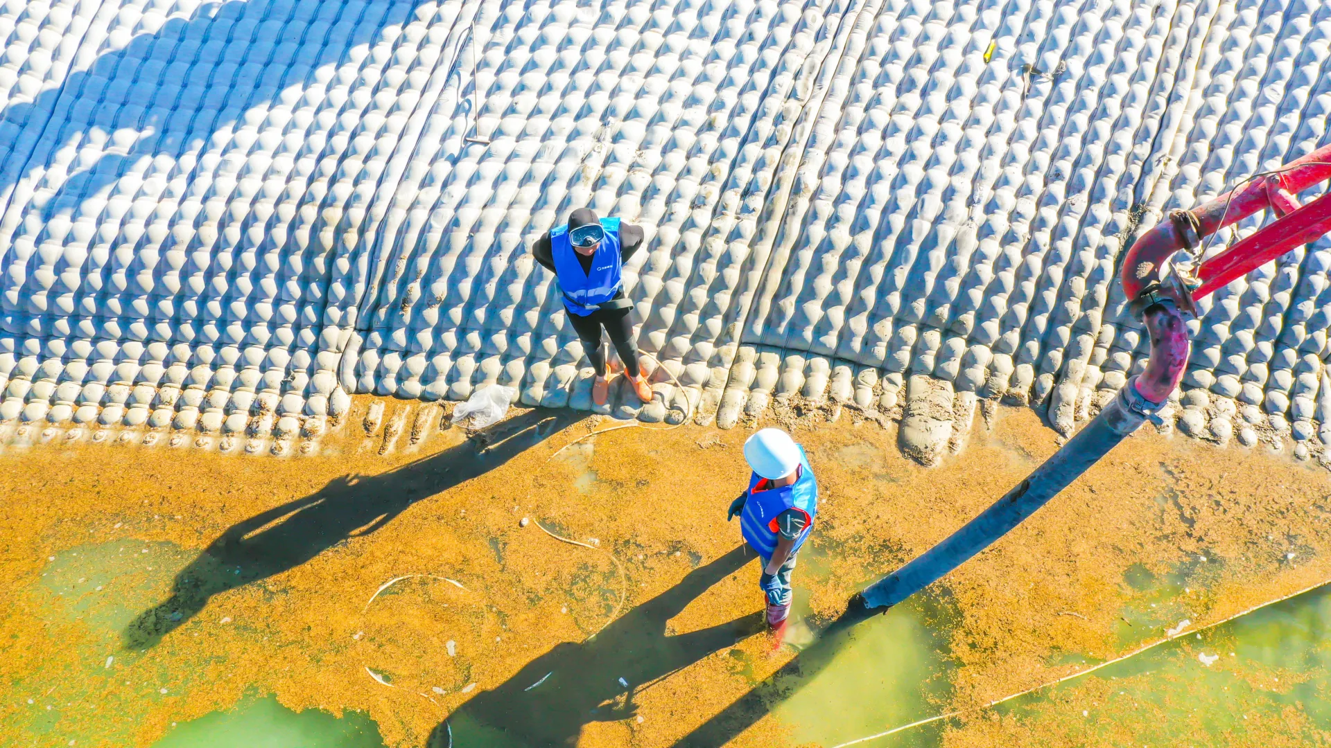Aerial view of workers installing grouted mattress on slope