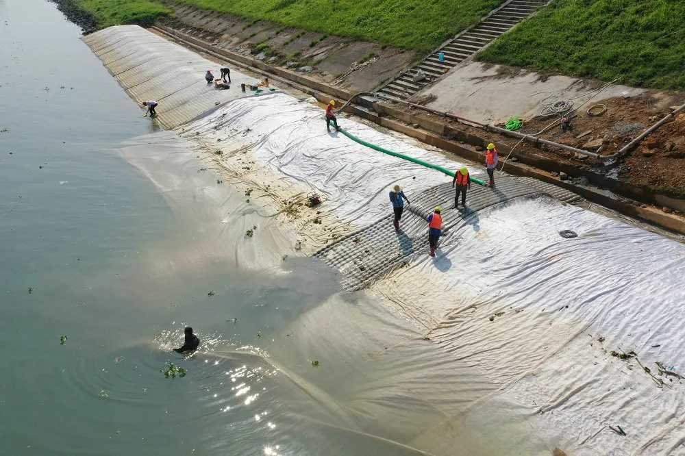 Workers installing filter point grouted mattress on coastal slope